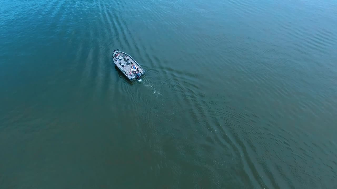 imágenes de drones de un bote bajo de camuflaje al ralentí alrededor de un pequeño lago en el sur de illinois