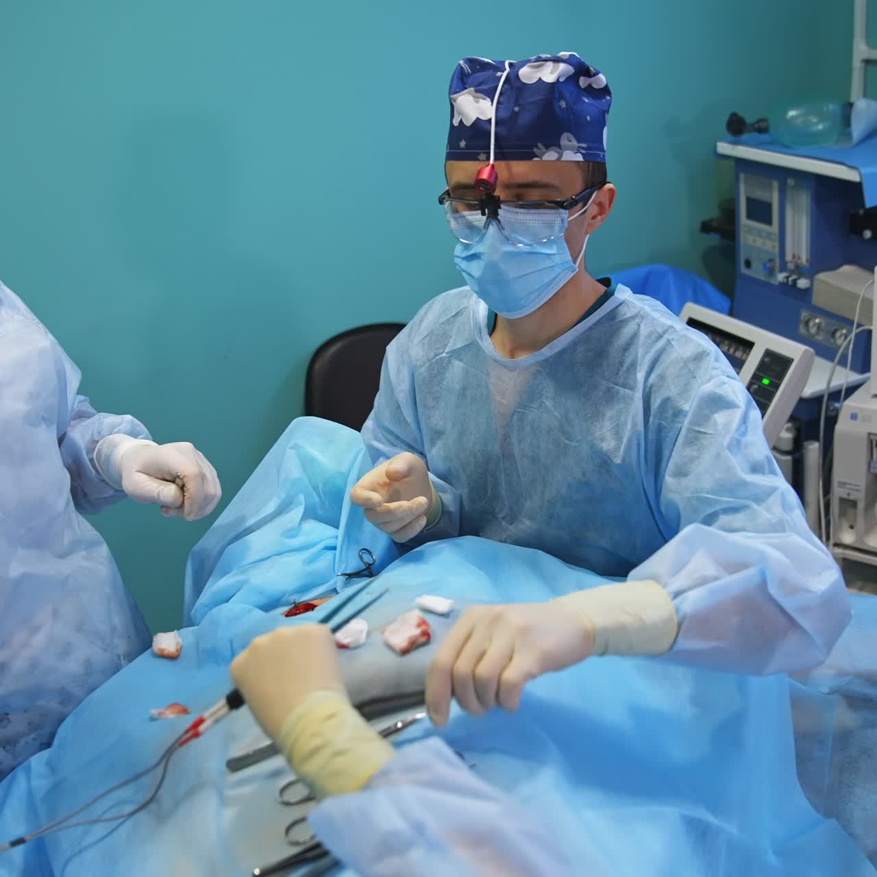 Doctors in device glasses using metal tools placed on the patient. Medical equipment behind the doctors at backdrop
