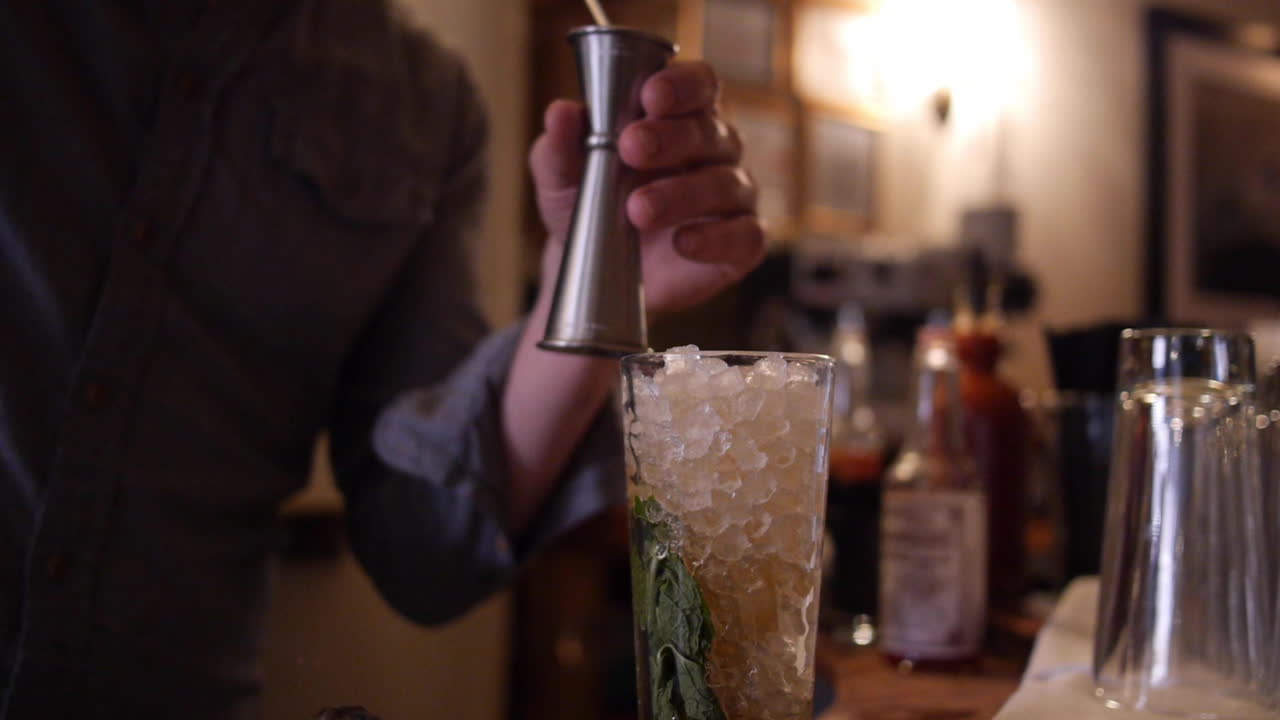 Bartender Adds Shots of Rum to Mojito Cocktail with Mint, Crushed Ice