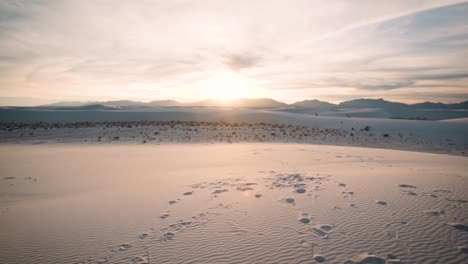 pan up over footprint covered white sand dunes at sunset