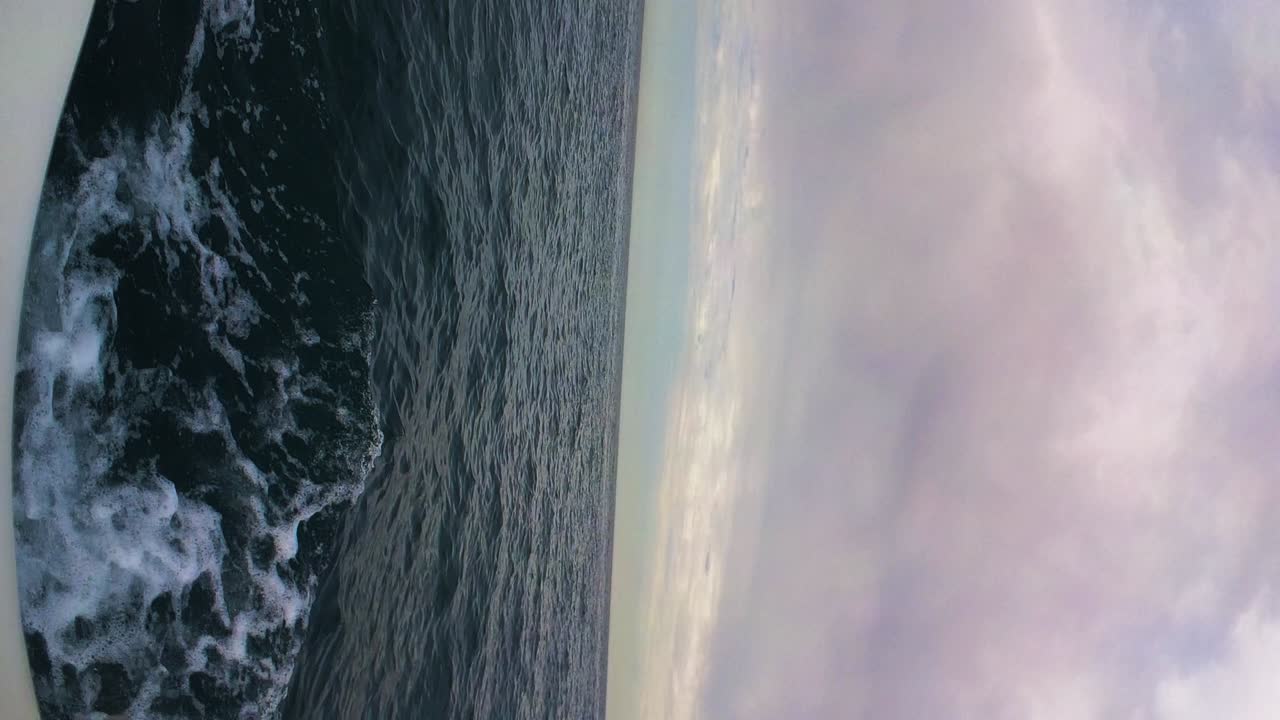 Sailing in open deep sea with moody cloudscape above, vertical view