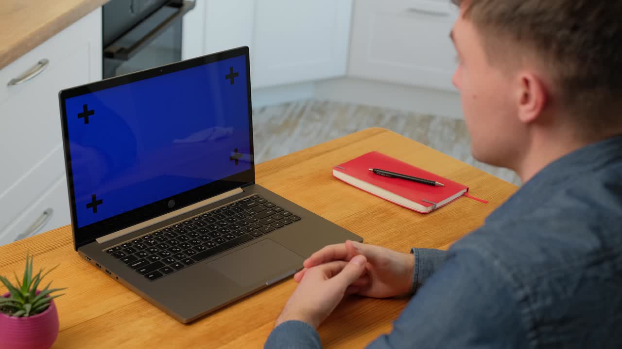 Man left view of smart man speaking with colleague while making video call on laptop with chromakey screen while working at home.
