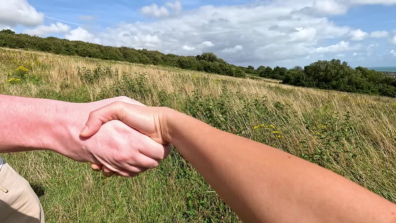 dos personas estrechando la mano en un campo