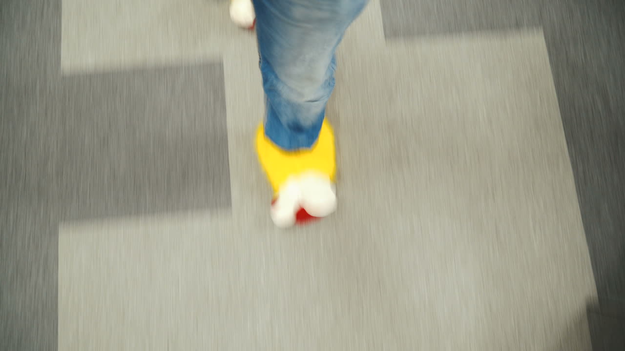 Office employee in funny yellow slippers. Male feet close-up walking through the office.