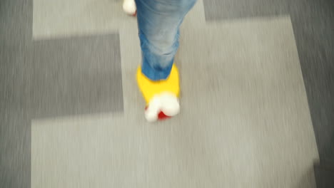 office employee in funny yellow slippers. male feet close-up walking through the office.