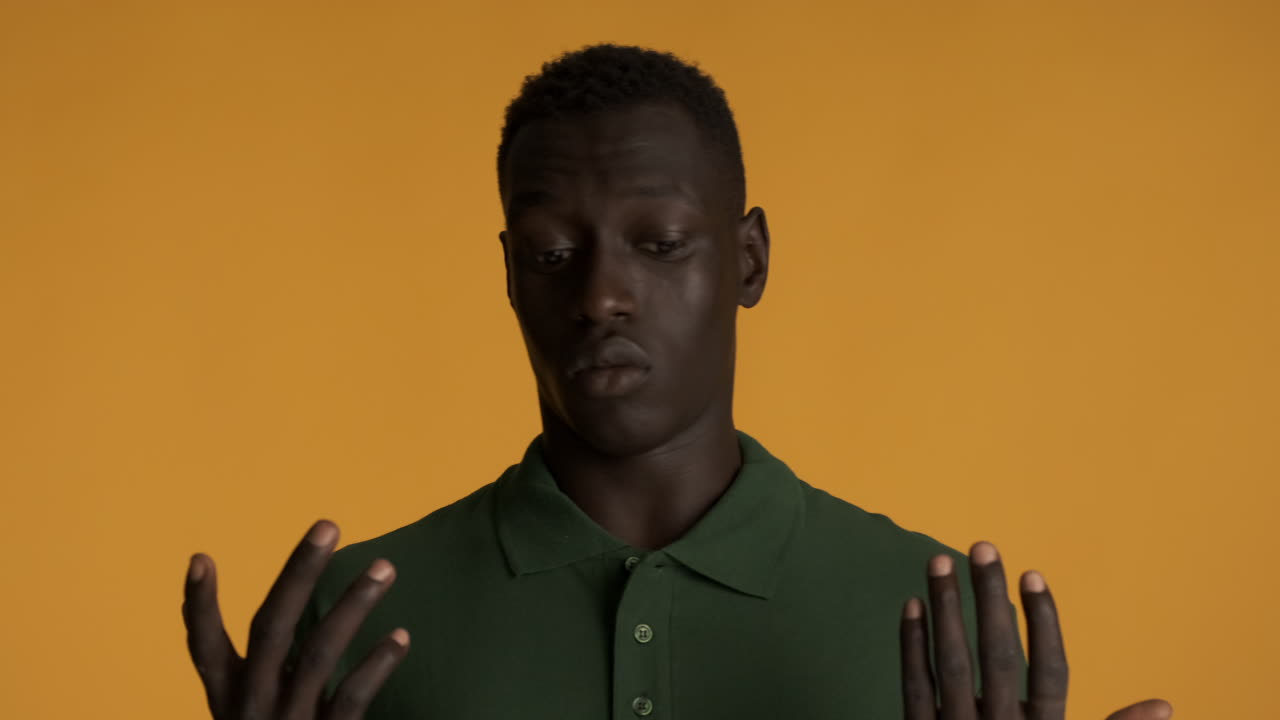 Scared African american man on yellow background.