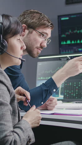 financial analysts work on multi-monitor computer with real-time stocks and exchange market charts in bank office. big digital screen showing tv news broadcast. vertical shot