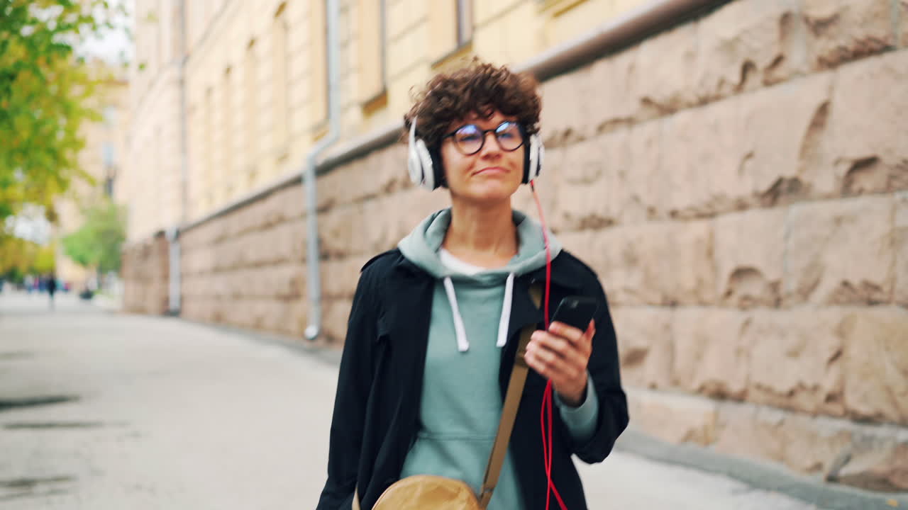 Young Woman Walking and Listening to Music in the City