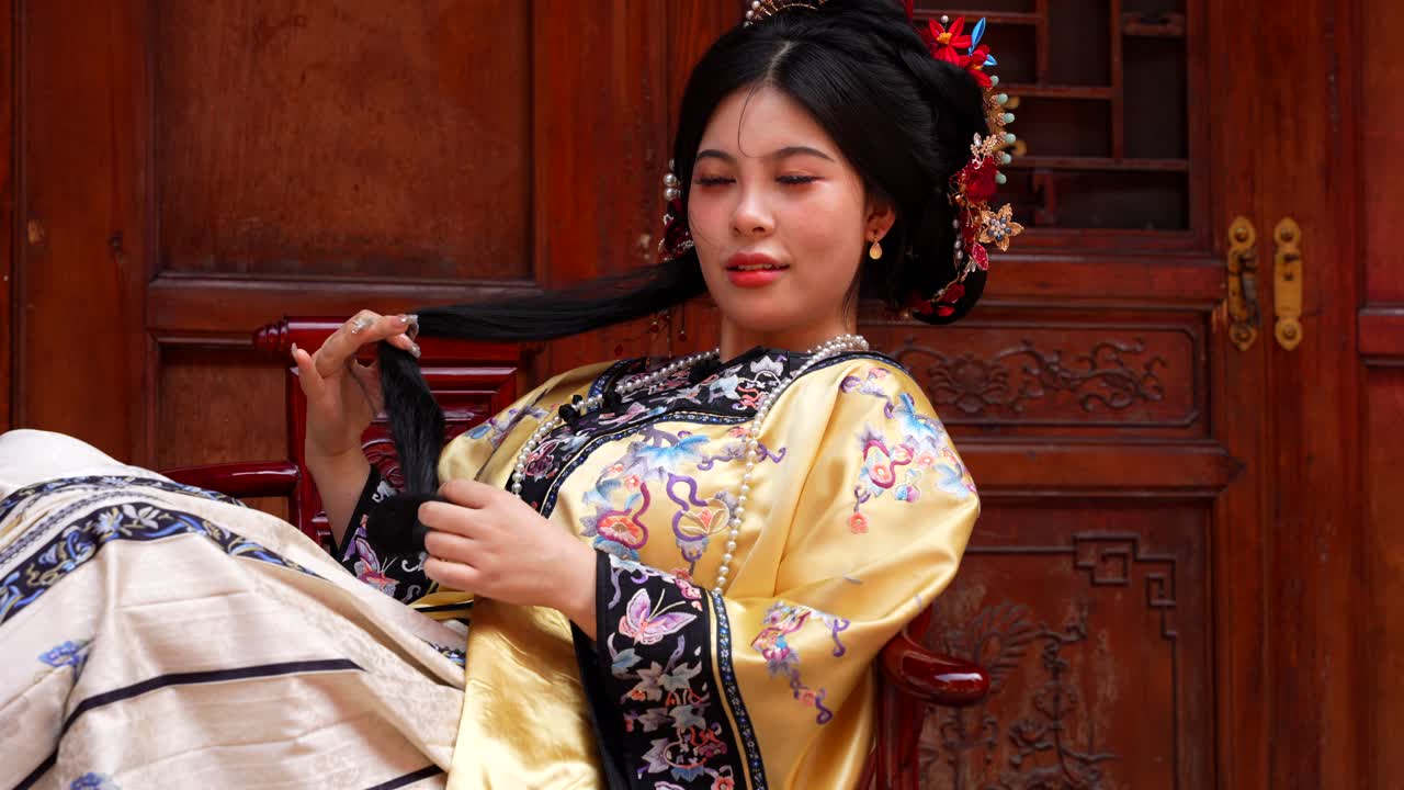 Beautiful Chinese woman in traditional Qing Dynasty dressed playing with her ponytail