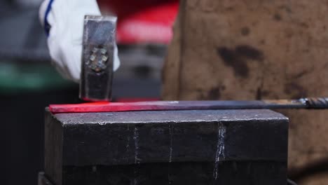 Blacksmiths-forging-hot-metal-with-hammer-in-workshop