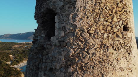 close up view of stone fort rising above mediterranean beaches in sardinia, italy