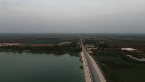 Lonely road along lake with farmland in Tay Ninh, South Vietnam at sunset