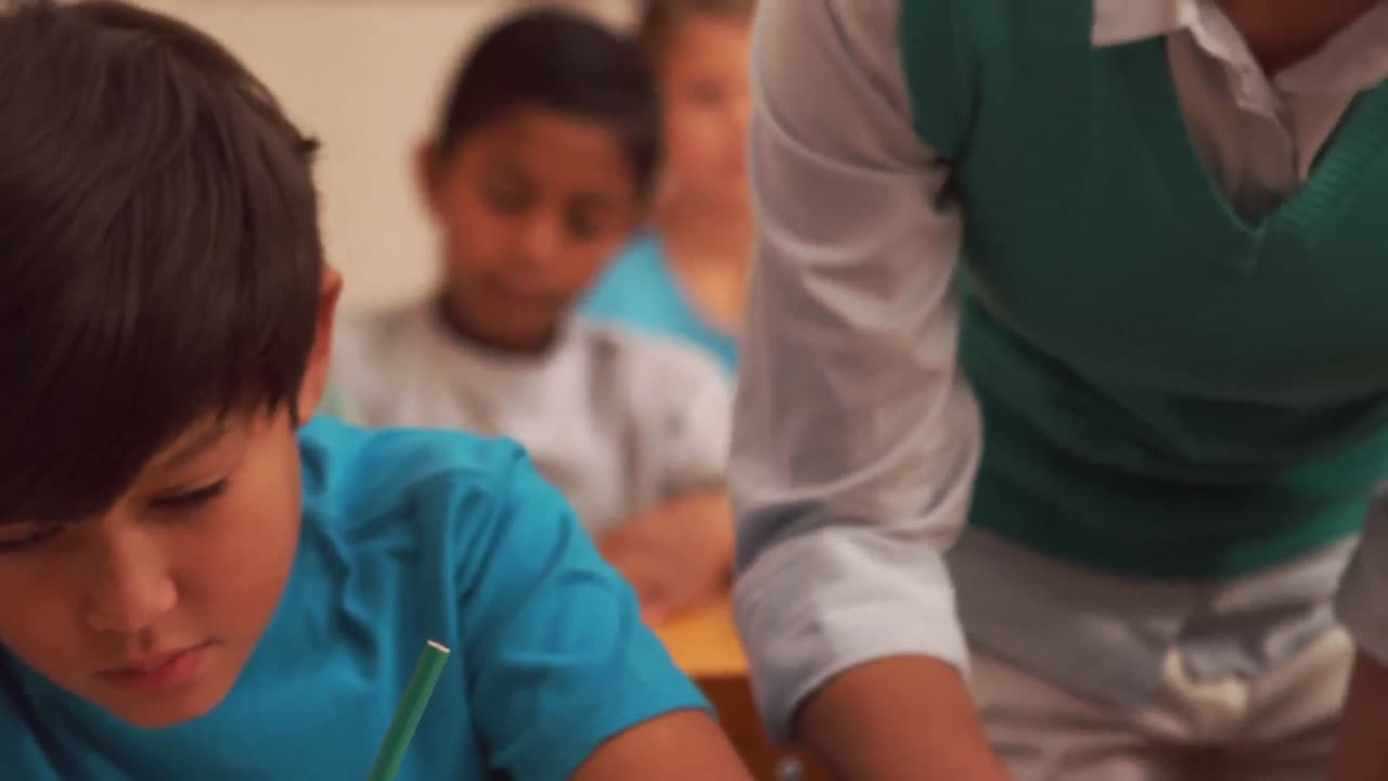 niño escribiendo mientras la joven maestra bonita está a su lado