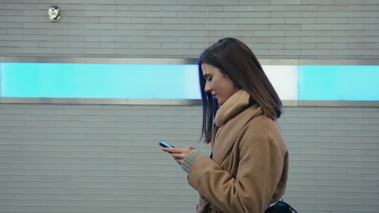 지하철역에서 스마트폰을 사용하는 여성