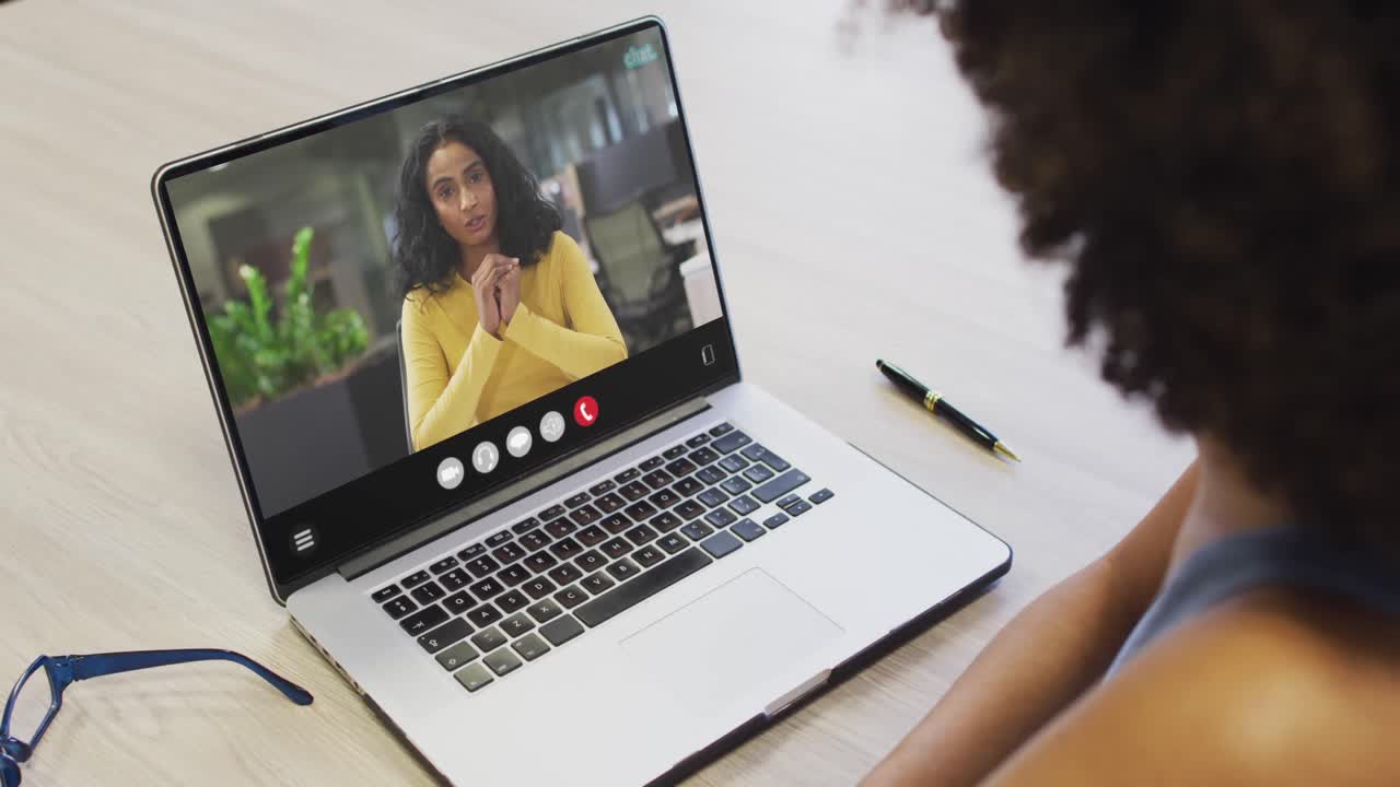 African american woman using laptop for video call, with business colleague on screen
