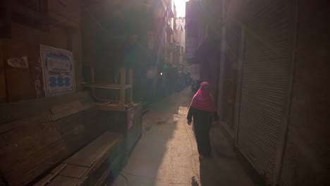 woman in a hijab walks down a narrow alley