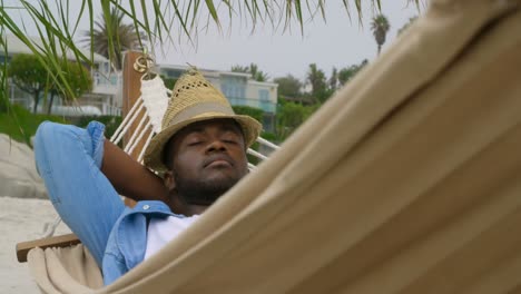 front view of african american man sleeping in a hammock on the beach 4k