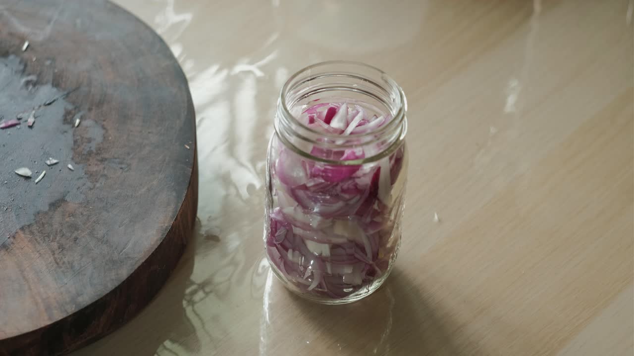 Hands sealing freshly sliced red onions in a mason jar. medium shot
