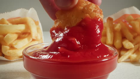 dipping chicken nuggets and french fries in ketchup