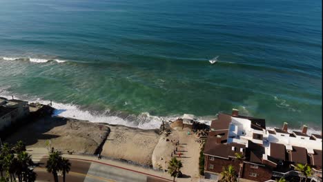 aerial of a surfer catching a wave off a private beach with homes