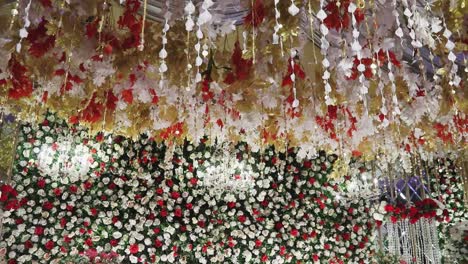 the stage is adorned with vibrant flowers and an elegant white chandelier, captured in a close-up shot with a panning view