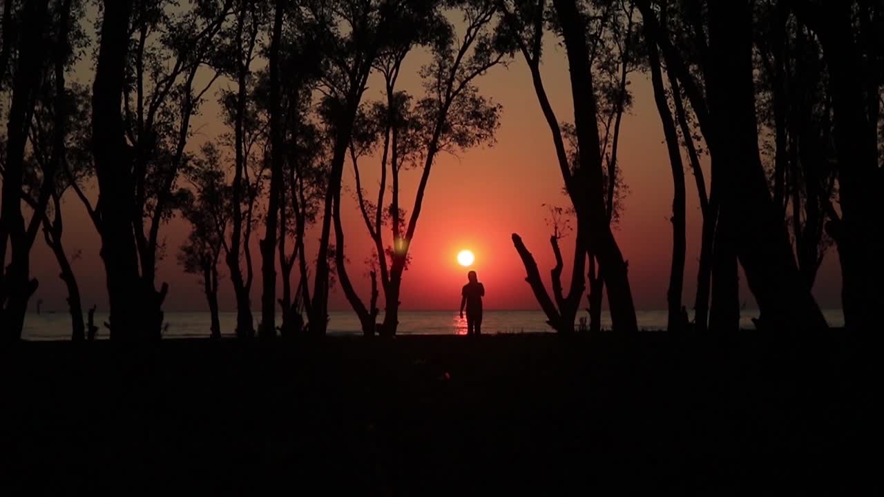 素晴らしい島の夕日、太陽を背にしてビーチを歩く人のシルエット