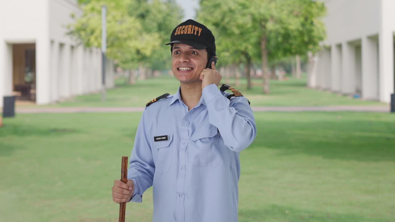 Happy Indian security guard talking on phone