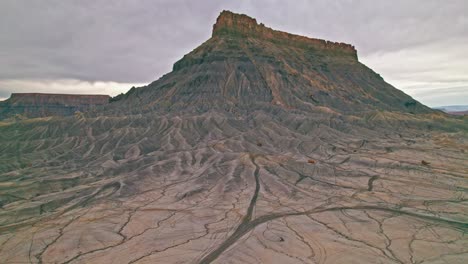 utah’s factory butte badlands, with deeply eroded gullies, sharp ridgelines, dramatic desert topography with intricate textures and earthy tones, rugged, otherworldly terrain by 4k drone