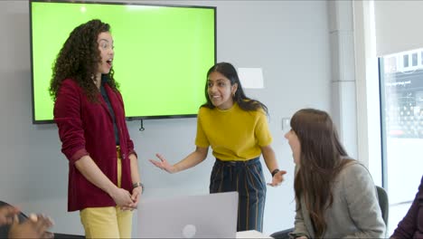 smiling colleagues clapping and high fiving with green screen tv