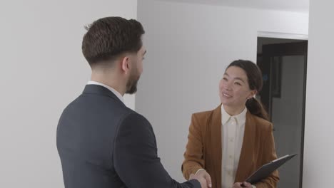 positive male candidate leaving office after job interview in office by female interviewer