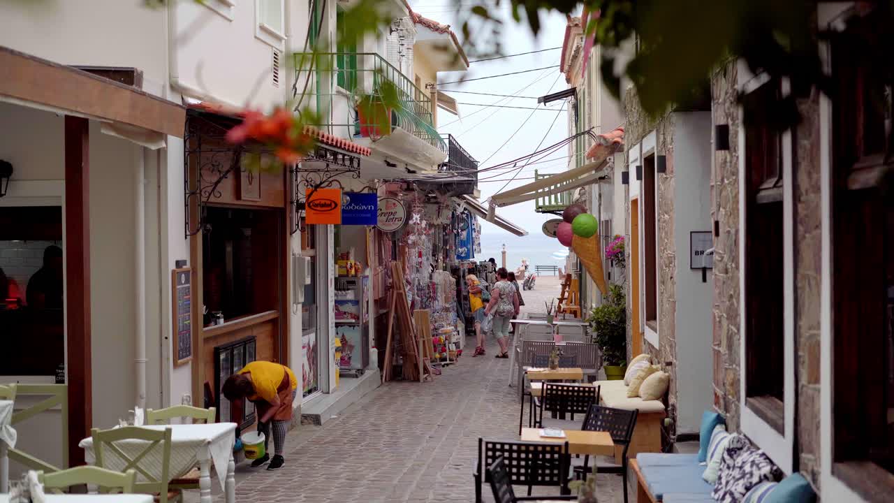 Seafront village Petra narrow cobblestone street with tavernas, shops, Gimbal shot