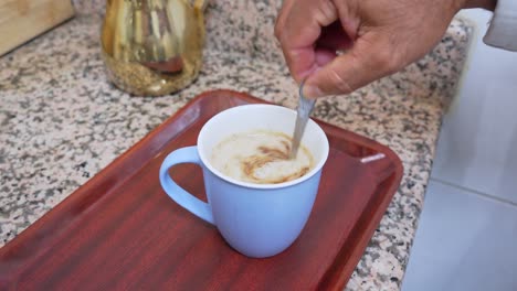 full sequence of hot milk being poured into a blue mug and stirred on kitchen tray. perfect for food content, breakfast scenes, hospitality, or cozy lifestyle visuals.