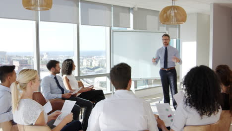 Businessman-Making-Presentation-To-Colleagues-In-Office