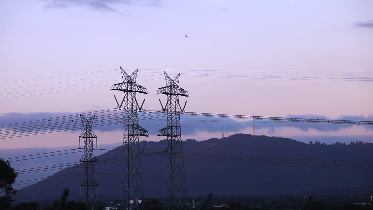 Plane flying in a circle to practice aerial circuits with power lines hanging in the foreground and lovely rolling hills in the background.