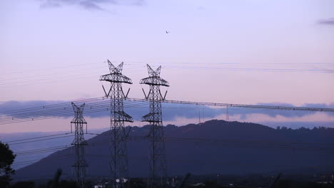 plane flying in a circle to practice aerial circuits with power lines hanging in the foreground and lovely rolling hills in the background.