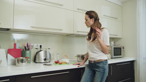 Mujer-Feliz-Bailando-Con-Teléfono-Móvil-En-La-Cocina-Moderna