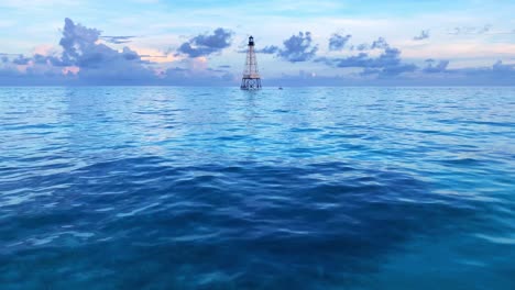 clip of the ocean and calm blue water witha a lighthouse in the background in alligator reef light in florida keys