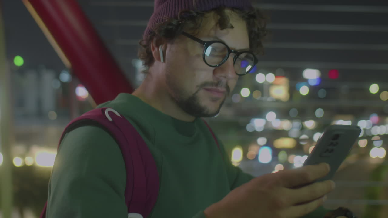 Young Man Using Smartphone on Bridge in Night City