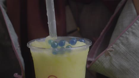 woman drinking a yellow boba slushy