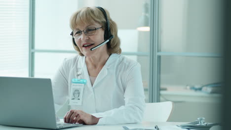 senior female doctor giving online consultation via web call in clinic