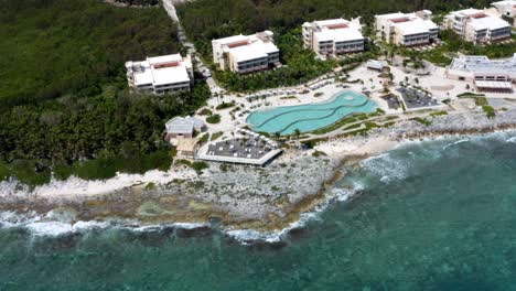 beautiful spinning aerial drone view of the tropical coastline of playa del carmen with large vacation resorts with pools and bars in riviera maya, mexico on a warm sunny summer day