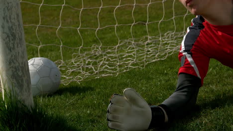 goalkeeper in red letting in a goal during a game