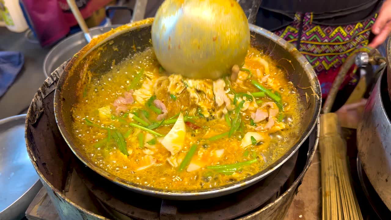 A vibrant street vendor prepares a bubbling suki hot pot, showcasing fresh ingredients and dynamic cooking techniques in a bustling Bangkok setting