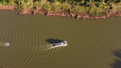 Toma-Aérea-De-Arriba-Hacia-Abajo-Del-Barco-Turístico-Y-Lancha-Rápida-Navegando-En-El-Río-Iguazú-Durante-El-Día-Soleado---Visitando-El-País-De-Argentina-Y-Brasil