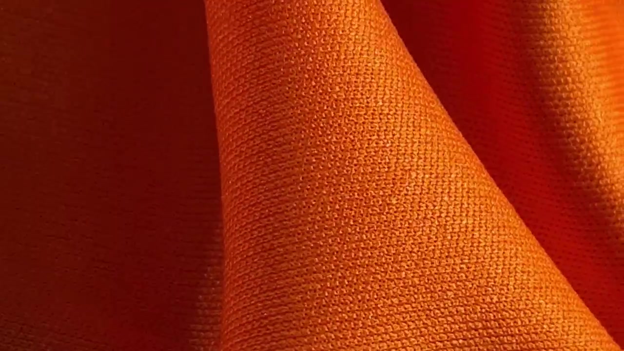 Detailní záběr zářivě oranžové textury látky.