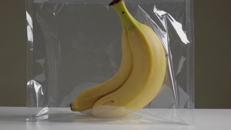 two bananas creatively displayed in a clear vacuum sealed bag, highlighting freshness and modern preservation techniques. the minimalist setup emphasizes the concept of food storage