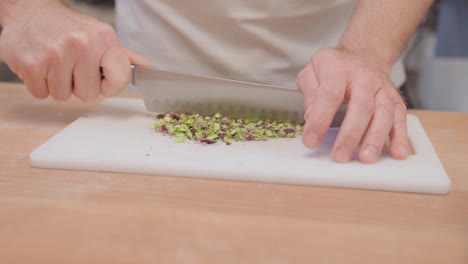 close-up of hands chopping pistachios on a cutting board in slow motion