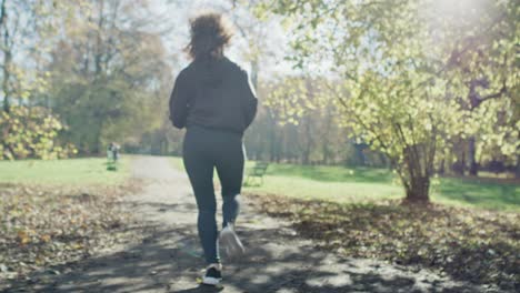 Vista-Trasera-De-Una-Mujer-Pelirroja-Corriendo-En-El-Parque-En-Otoño