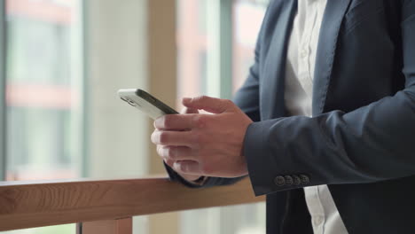 the hands of a businessman in a blue blazer consults his smart phone and write on it 1