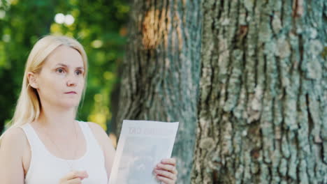 young woman attaches an ad to a tree in the park